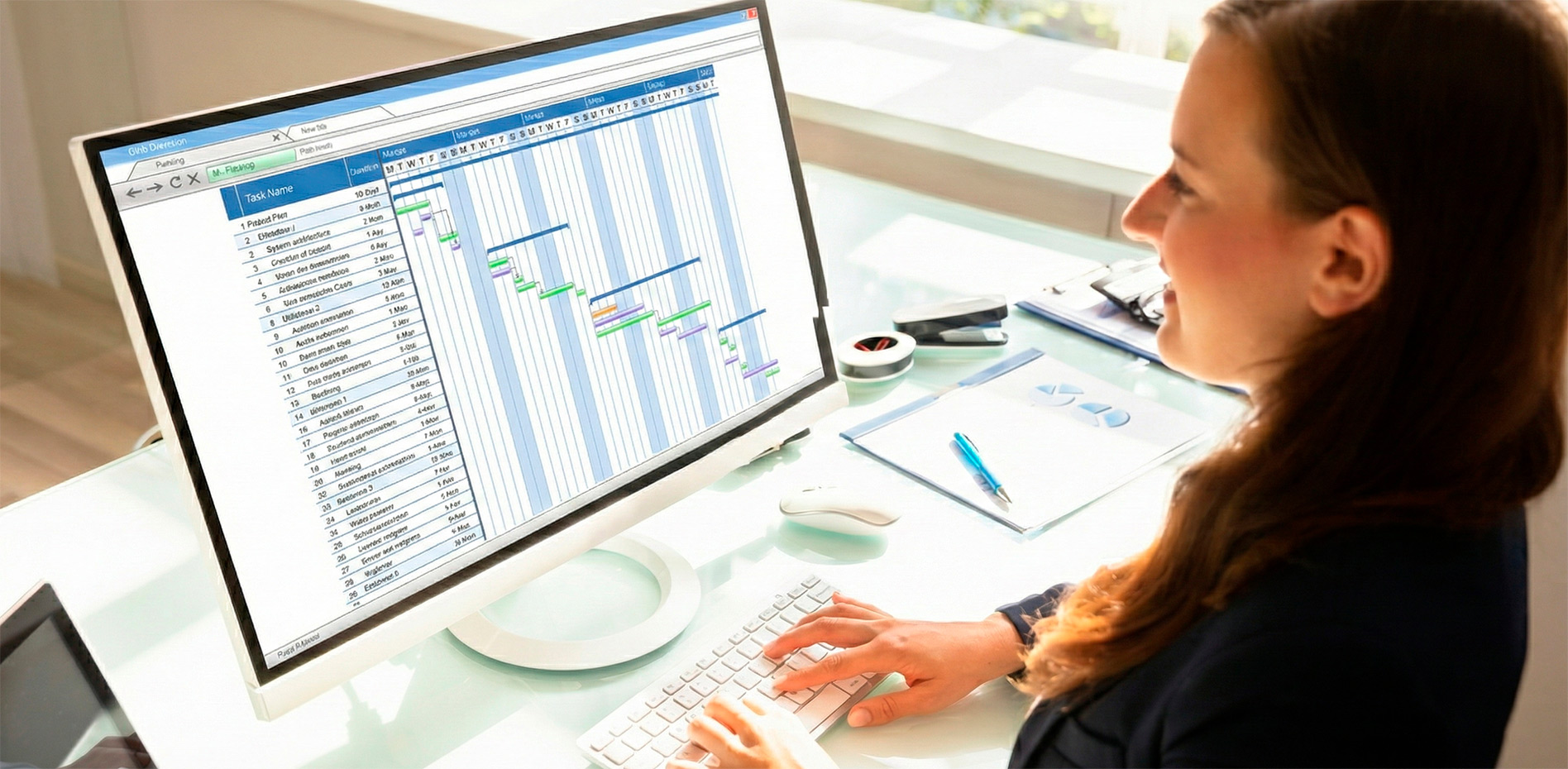 gestion-proyectos-diagrama-gantt-planificacion-software-innk Una profesional en una oficina iluminada trabaja en una computadora de escritorio analizando un cronograma complejo con diagrama de Gantt, representando el control detallado de tiempos y tareas.