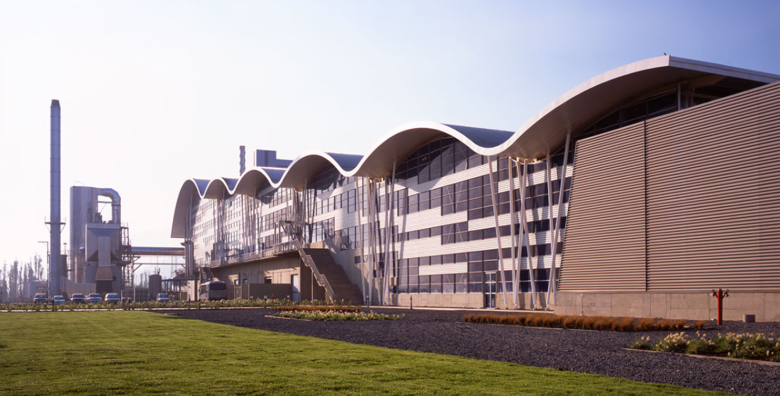 Casos de Éxito. Fachada de planta industrial moderna con diseño arquitectónico de techos ondulados, representando la eficiencia operativa y la infraestructura estratégica gestionada por INNK.