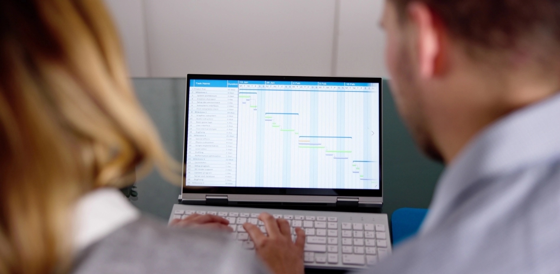 diagrama-gantt-planificacion-gestion-proyectos-innovacion Dos profesionales analizando un diagrama de Gantt en la pantalla de una laptop para la planificación de cronogramas y el seguimiento detallado en la gestión de proyectos de innovación empresarial.